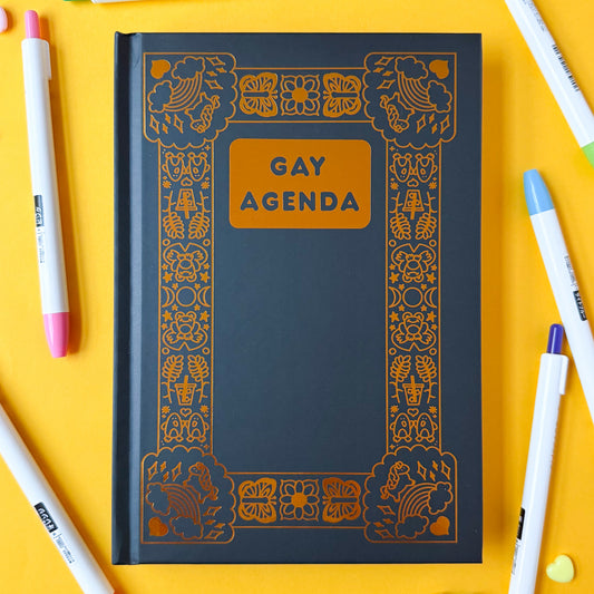 The Gay Agenda on a yellow background surrounded by colorful pens.