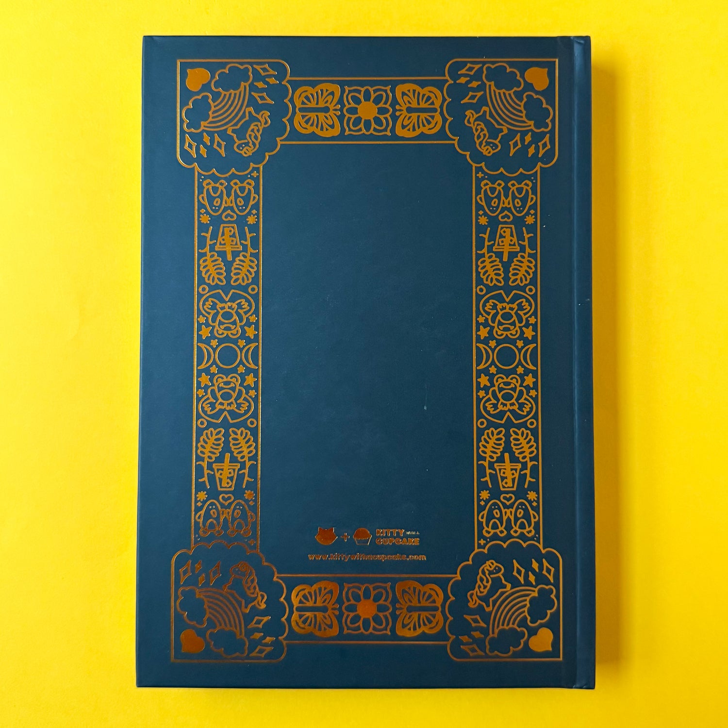 The back of the gay agenda on a yellow background. The back has the same illustrated border as the front, but with the Kitty With a Cupcake logo in the bottom center.