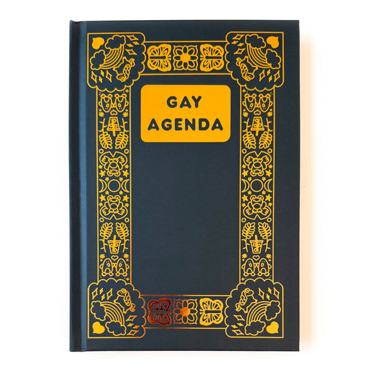 A hard covered black notebook with gold foil details. The title “Gay Agenda” is in the top center, and the notebook has an ornate boarder filled with queer themed illustrations. A few examples of these illustrations are rainbows, unicorns, penguins, butterflies, and iced coffees.