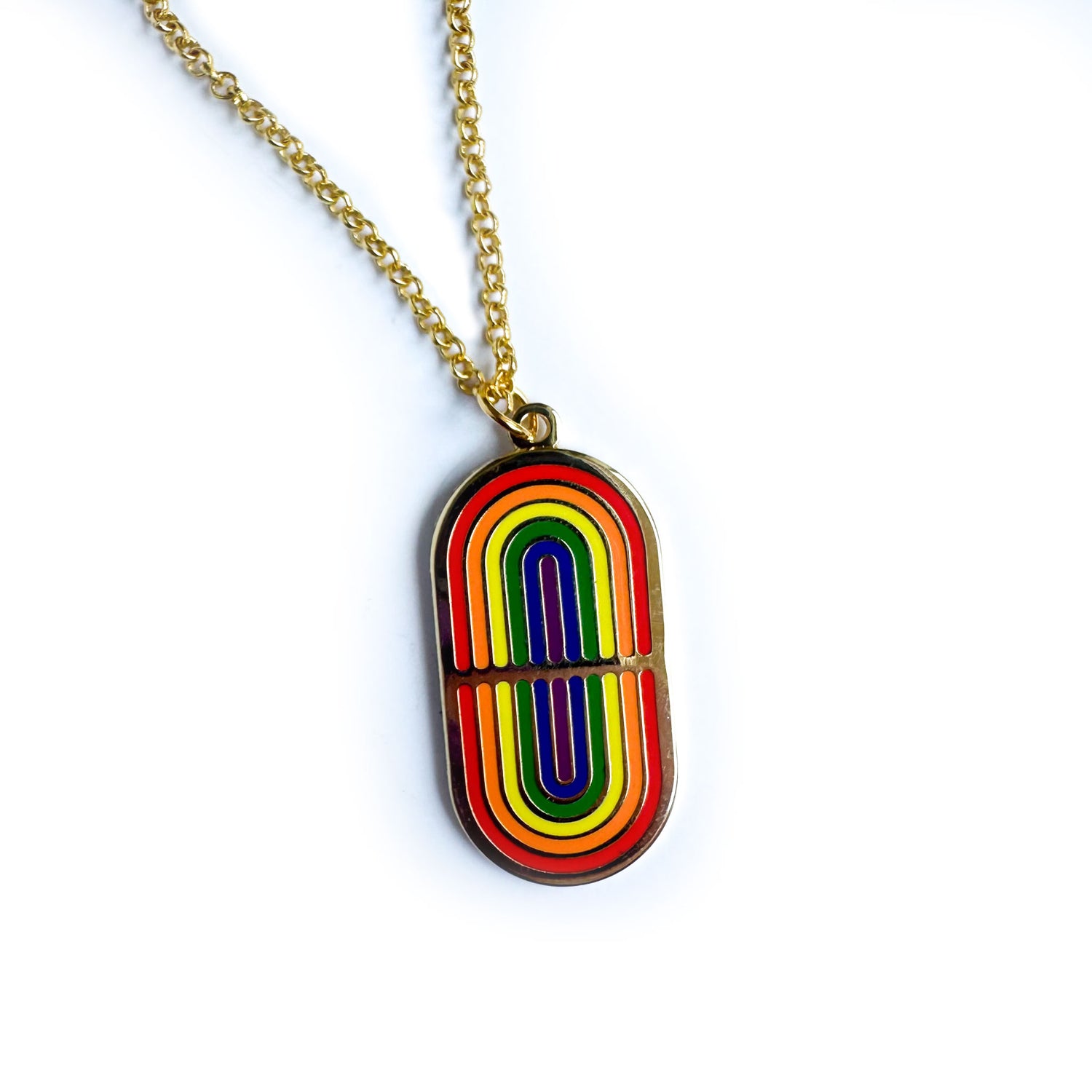 A pendant style necklace with an oval shaped pendant with two mirrored rainbows on it in hard enamel. 