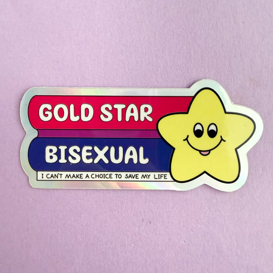 Product photo of the Gold Star Bisexual sticker. The sticker has a cute yellow star illustration on the right. The star has eyes and a smile with its tongue sticking out. On the left is a stripe of hot pink and "GOLD STAR" in white text, a purple stripe below that, and a blue stripe at the bottom with "BISEXUAL" in white text. At the bottom is a stripe of white with "I can't make a choice to save my life" in black text at the bottom. The border of the sticker is holographic. All on a purple background.