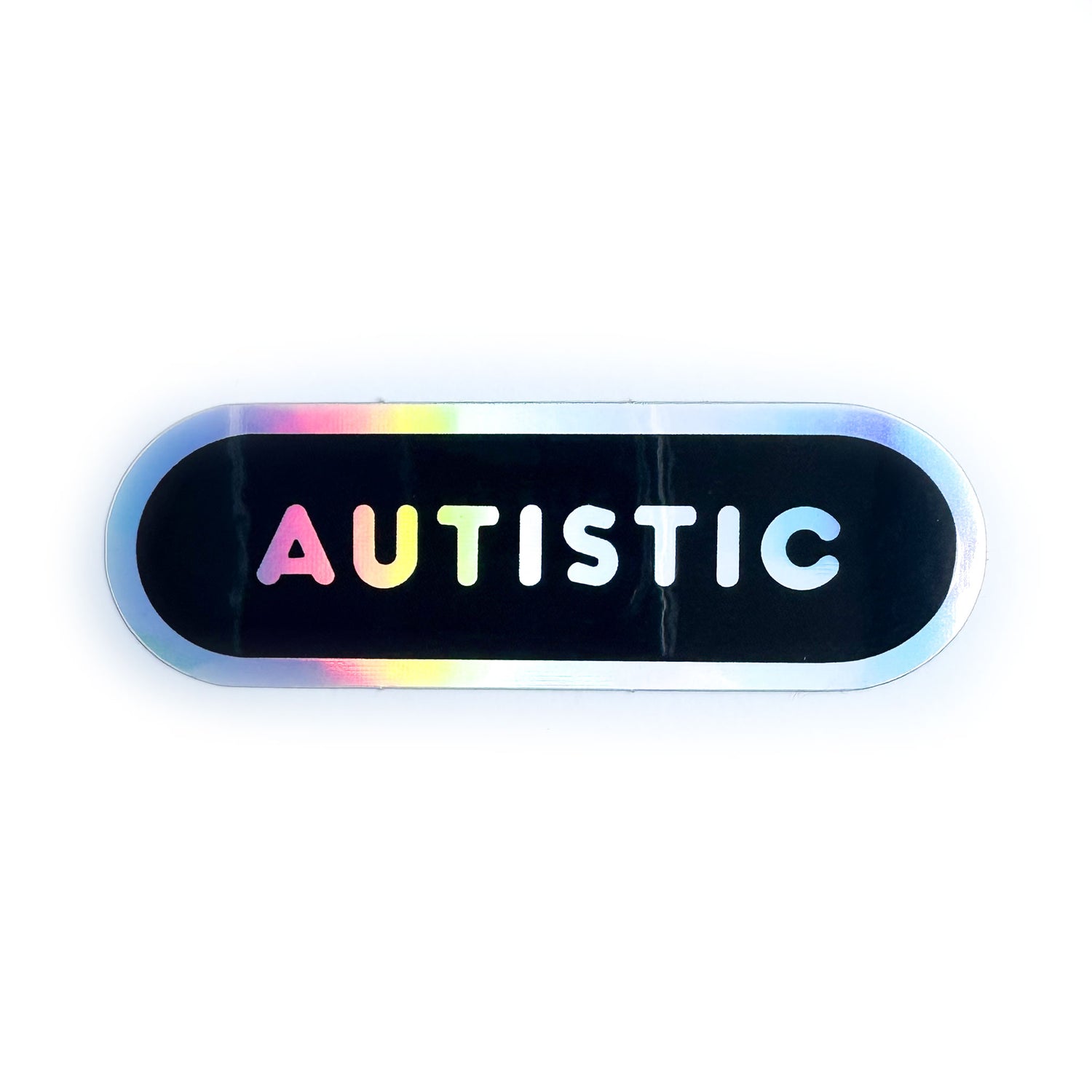 A black capsule shaped sticker with holographic border and holographic bubble letters that read "Autistic"