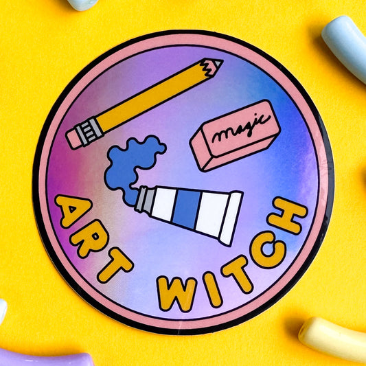 A circular sticker in the style of a merit badge that reads "art witch" it features an illustration of a tube of paint, a yellow pencil, and a pink eraser that reads "magic" on it.
