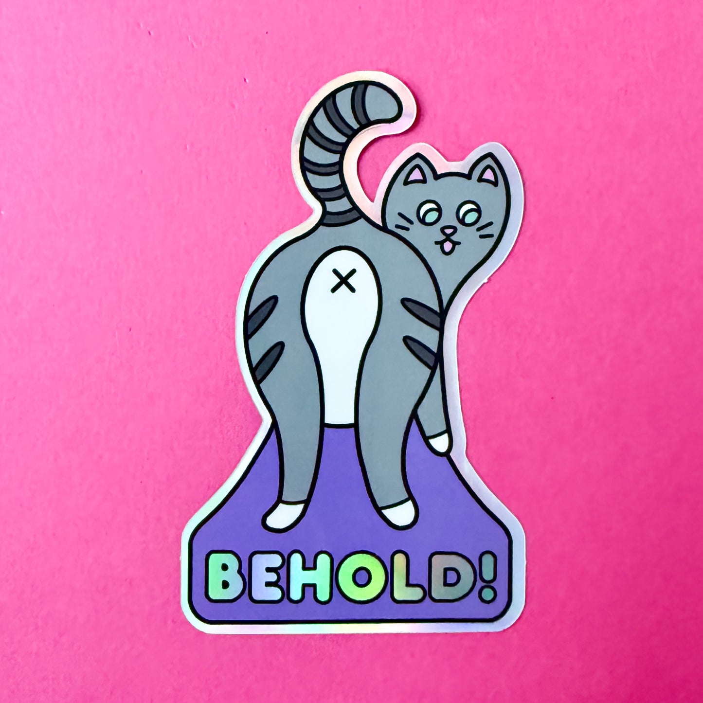 The Behold! sticker on a hot pink background.