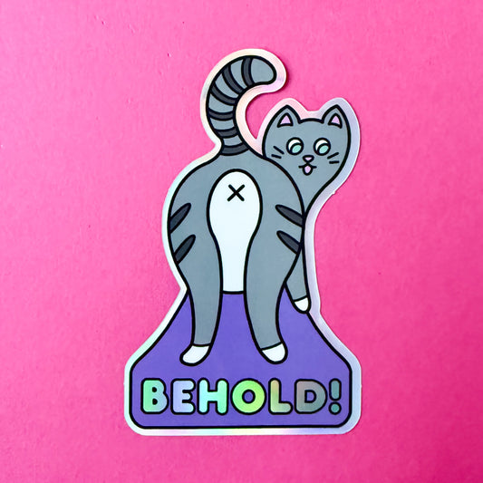 The Behold! sticker on a hot pink background.