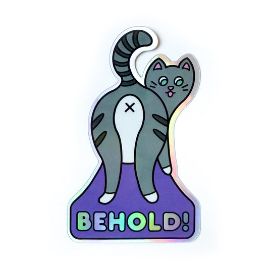 A holographic sticker featuring a grey striped cat presenting you their butthole. Below the cat on a purple background in holographic letters is the word “BEHOLD!”.