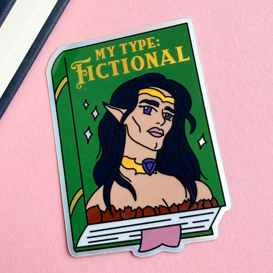 A sticker depicting a green book with the title “My Type: Fictional” written in gold. There is a hot androgynous elf on the cover with long black hair, big purple eyes, and luscious pink lips. They have sharp features, high cheek bones, and a chiseled jaw. They are wearing a gold crown, a gold choker with a purple gem, and an off-the-shoulder brown top. The book has gold accents on the spine, white sparkles on the cover, and a pink bookmark sticking out of the bottom. This sticker is on a pink background.