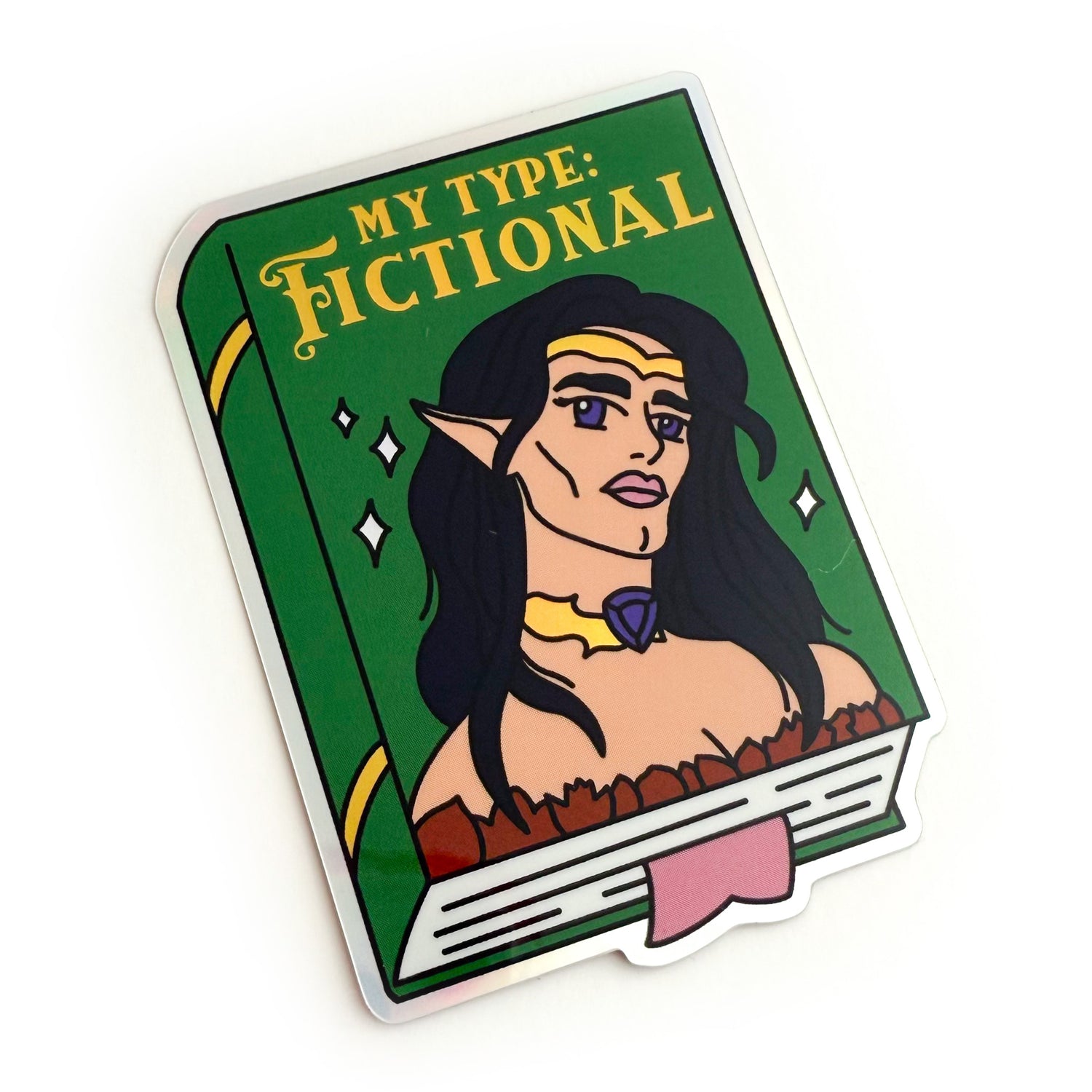 A sticker depicting a green book with the title “My Type: Fictional” written in gold. There is a hot androgynous elf on the cover with long black hair, big purple eyes, and luscious pink lips. They have sharp features, high cheek bones, and a chiseled jaw. They are wearing a gold crown, a gold choker with a purple gem, and an off-the-shoulder brown top. The book has gold accents on the spine, white sparkles on the cover, and a pink bookmark sticking out of the bottom.