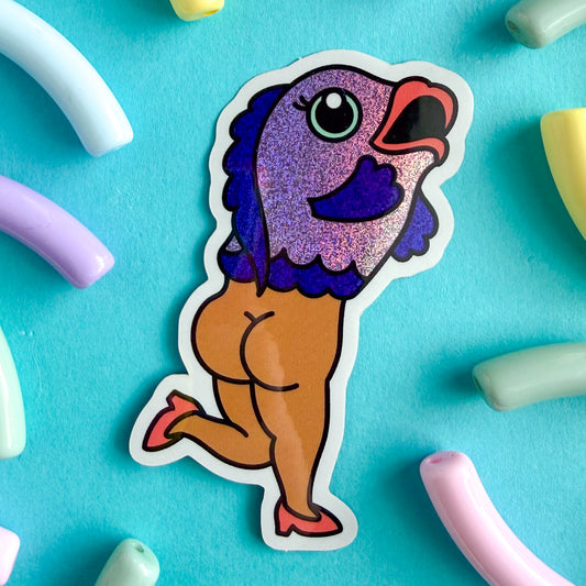 A glittery vinyl sticker of an illustration of a reverse mermaid, a fish on top and a nude lady on the bottom with cheeks out and high heels on. The sticker is on a blue background with beads around it.
