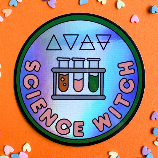 A circular merit badge style holographic sticker with the words "science witch" on it and illustrations of a rack of test tubes and the alchemical symbols for the four elements.