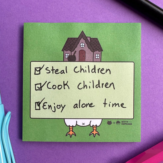 A square pad of green sticky notes featuring an illustration of Baba Yaga's house on a purple background with pens surrounding the pad. There is a to-do list written on the pad that reads "Steal Children, Cook Children, Enjoy alone time" all of these items are checked off.