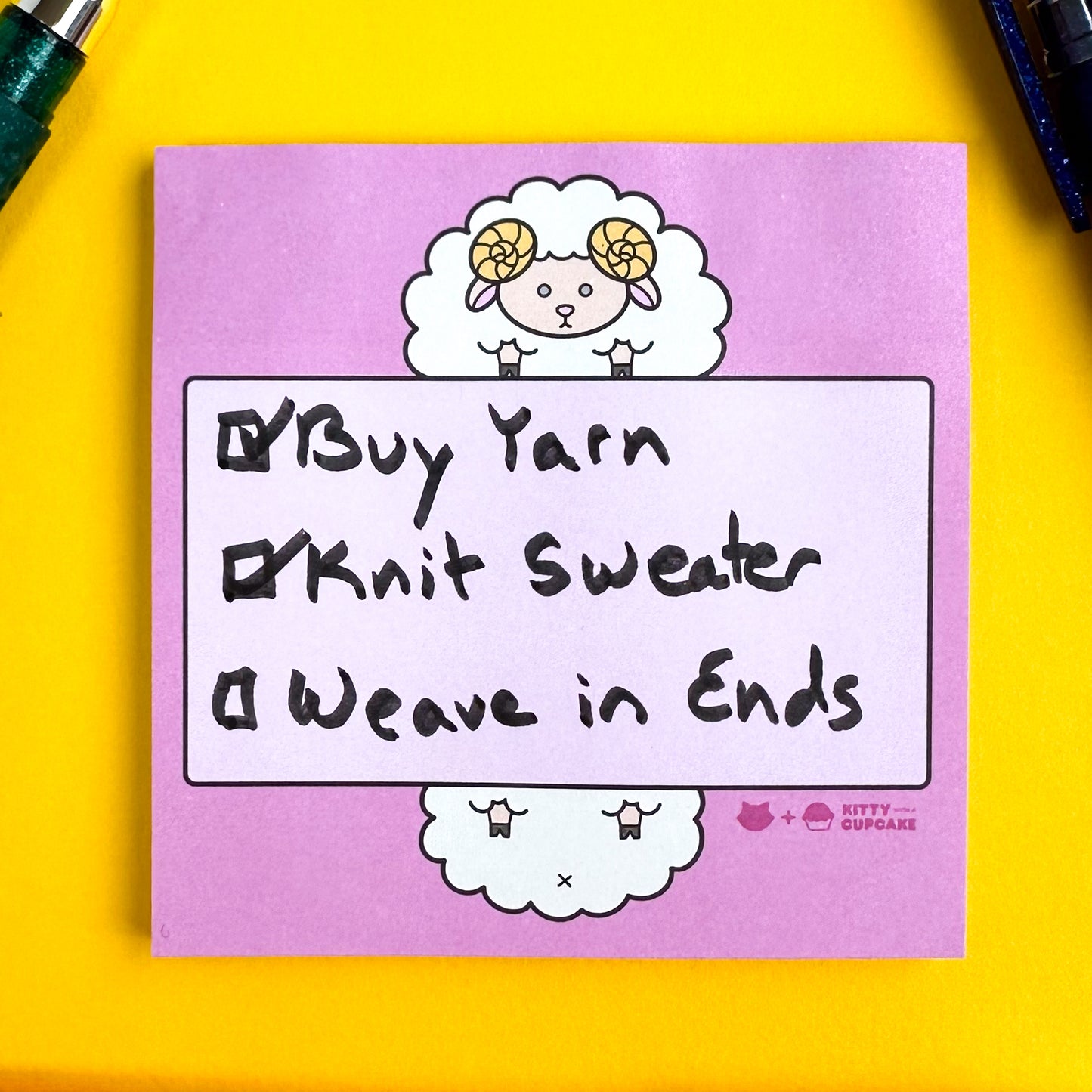 Pink sticky notes with a cute sheep illustration holding a light pink box with a handwritten checklist that reads "Buy Yarn, Knit Sweater, and Weave in Ends" the box by "Wave in Ends" is the only unchecked box. 