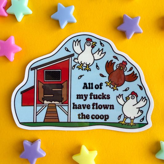 A vinyl sticker with an illustration of a chicken coop, two white chickens, and one brown chicken flying chaotically flapping feathers. Under the chickens are the words "All of my fucks have flown the coop". The sticker is on a yellow background with star beads around it.