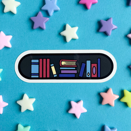 A capsule shaped sticker with illustrations of books to make it look like a bookshelf is on a blue background with pastel stars around it.
