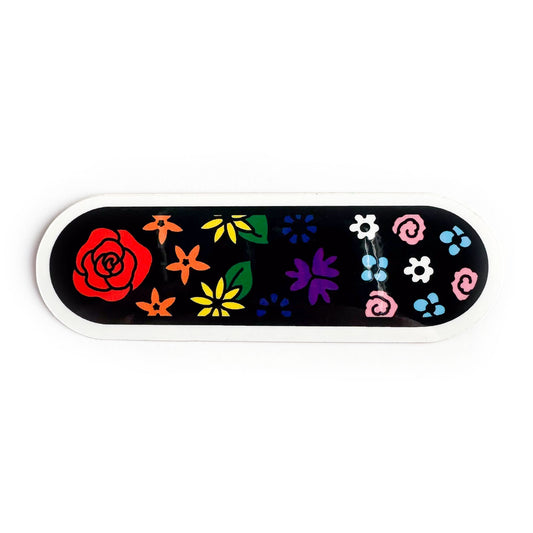 An oval shaped sticker with a black background with illustrations of flowers on it. The flowers are the colors of the rainbow pride and trans pride flags.