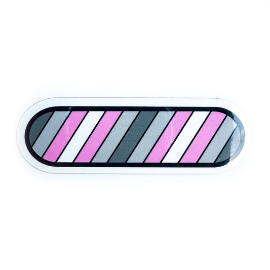 A capsule shaped sticker with stripes in the colors of the Demigirl Pride Flag in diagonal stripes across it.