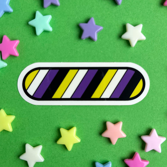An oval shaped sticker with diagonal stripes of the Nonbinary Pride flag. The sticker is on a green background with pastel star beads around it.