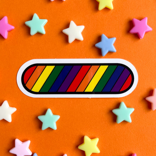 A sticker shaped like an oval with diagonal stripes of the rainbow across it. The sticker is on an orange background with pastel stars around it.