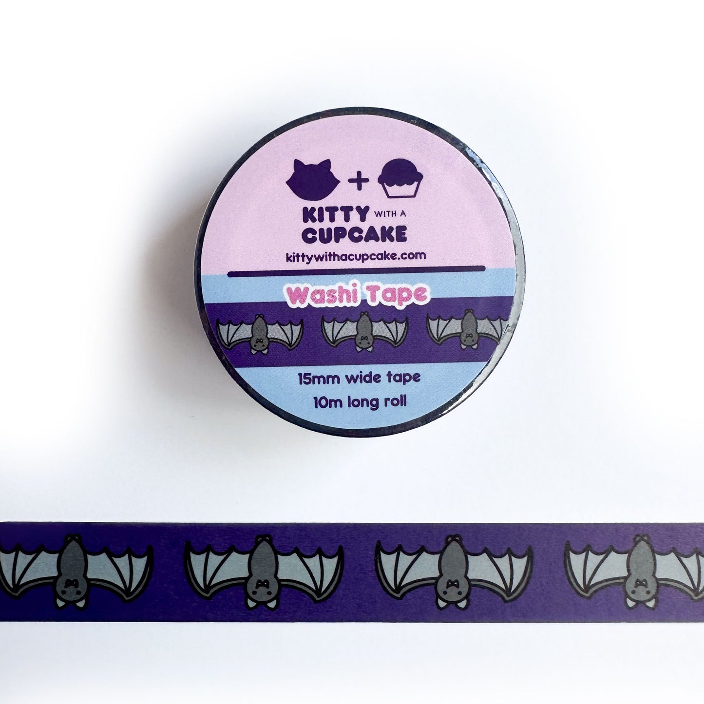 A roll of washi tape above a piece of the same tape. The tape has a dark purple background with cute bat illustrations on it. 