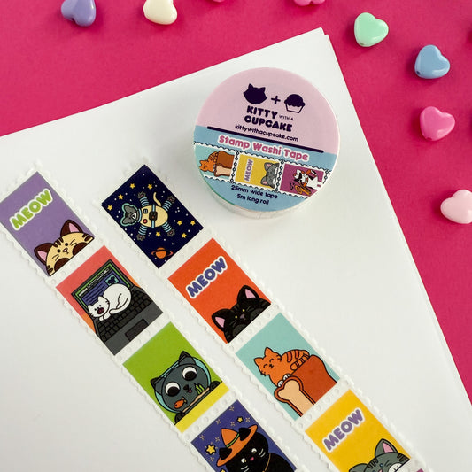 A roll of cat themed stamp washi tape. There is a packaged roll of tape with the Kitty With a Cupcake logo and an example of the tape inside. Below that are two displayed section of the tape, which is sectioned into stamp-style squares. Above are heart shaped decorative beads on a pink background.