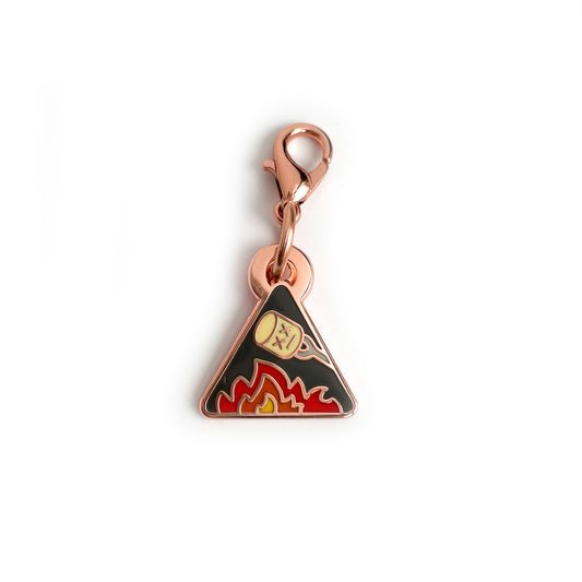 A triangle shaped charm with a marshmallow roasting over a flame.