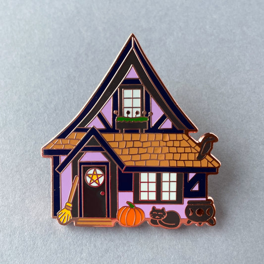 A purple tudor house shaped pin on top of a grey background.