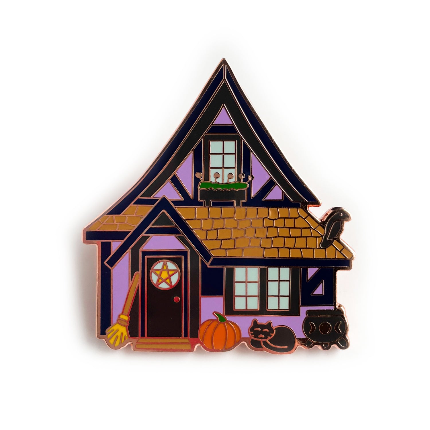 A tudor house shaped pin. The house is purple, it has a pentacle window, and a flower box. There is a raven perched on the roof and a cat sleeping in front of the house. There is a broom, pumpkin and cauldron outside. 