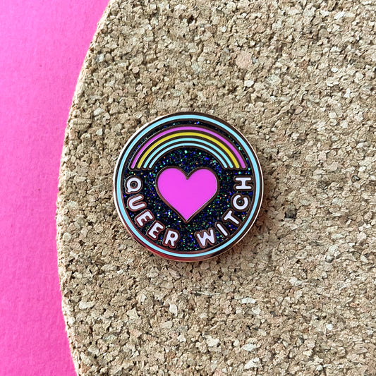 A circular pin on a cork board that reads "Queer Witch".