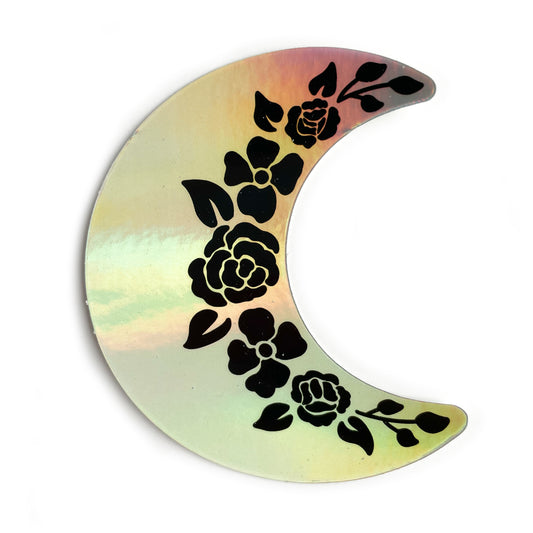 A crescent moon shaped holographic sticker. It has black floral outlines along the inside edge.