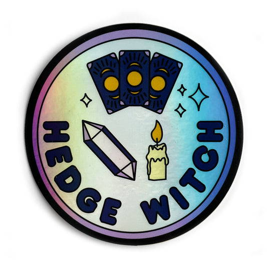 A circular holographic sticker with a purple border and words that read "Hedge Witch". It has an amethyst crystal, a candle, and tarot cards depicted on it.