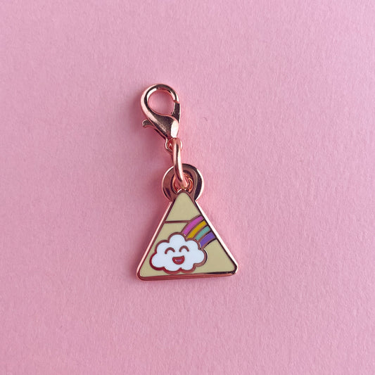 A triangle charm with a happy rainbow cloud on it on a pink background.