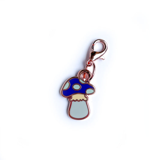 A mushroom shaped lobster claw clasp charm with a purple head and blue spots. 