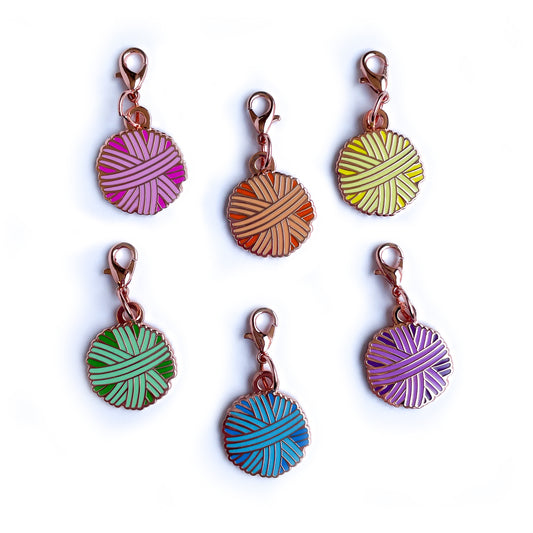 Six lobster claw clasp charms shaped like yarn balls in purple, orange, yellow, mint, blue, and purple. 