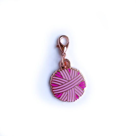 A yarn ball shaped charm in shades of pink with a lobster claw clasp.