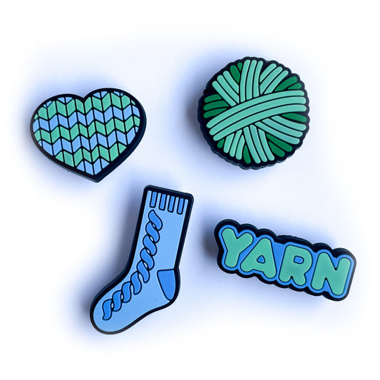 PVC charms shaped like a heart, a sock, a yarn ball and the word yarn in shades of mint green and pastel blue.