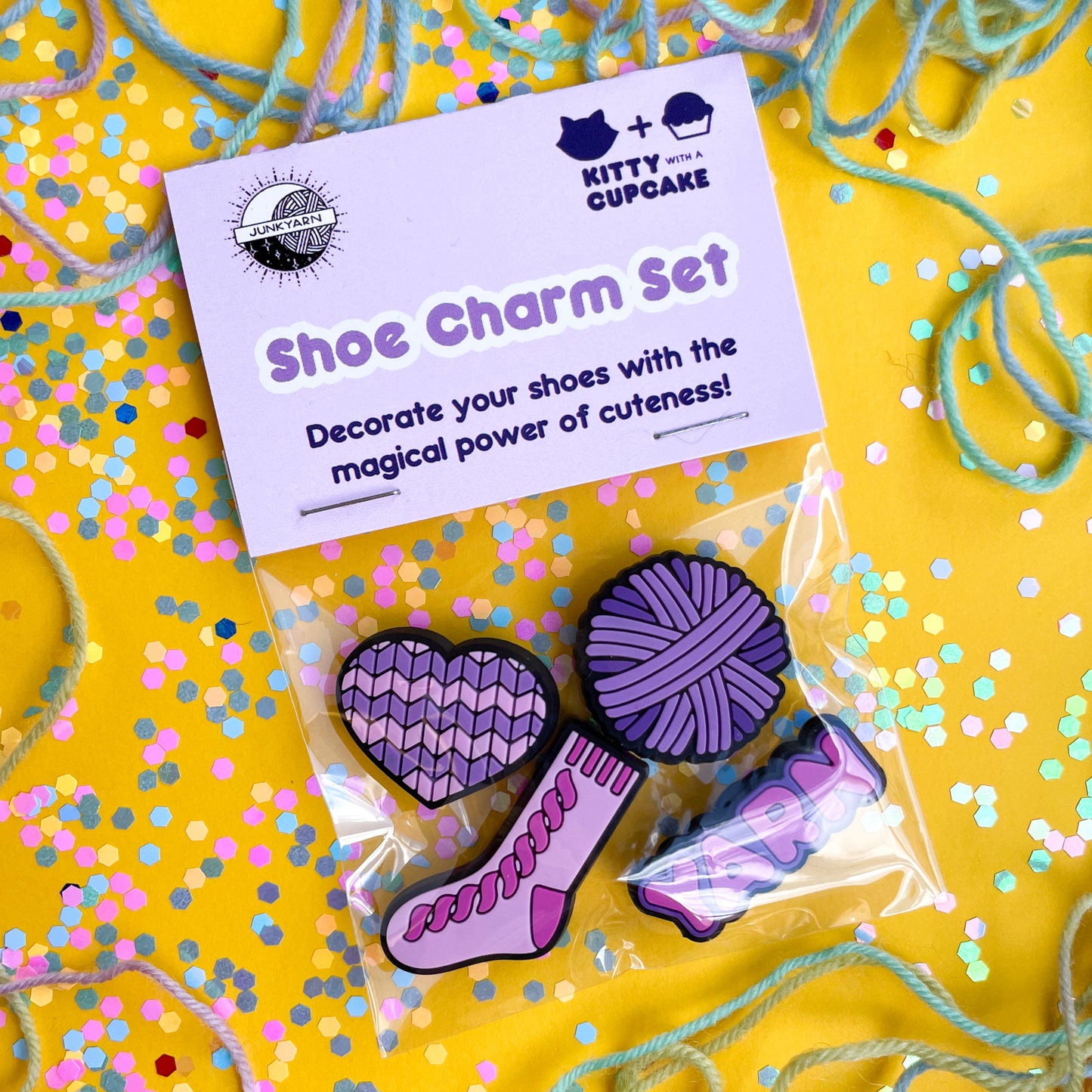A plastic bag with a header card that reads "Shoe charm set". The bag has charms in it shaped like a heart, yarn ball, sock, and the word yarn. 