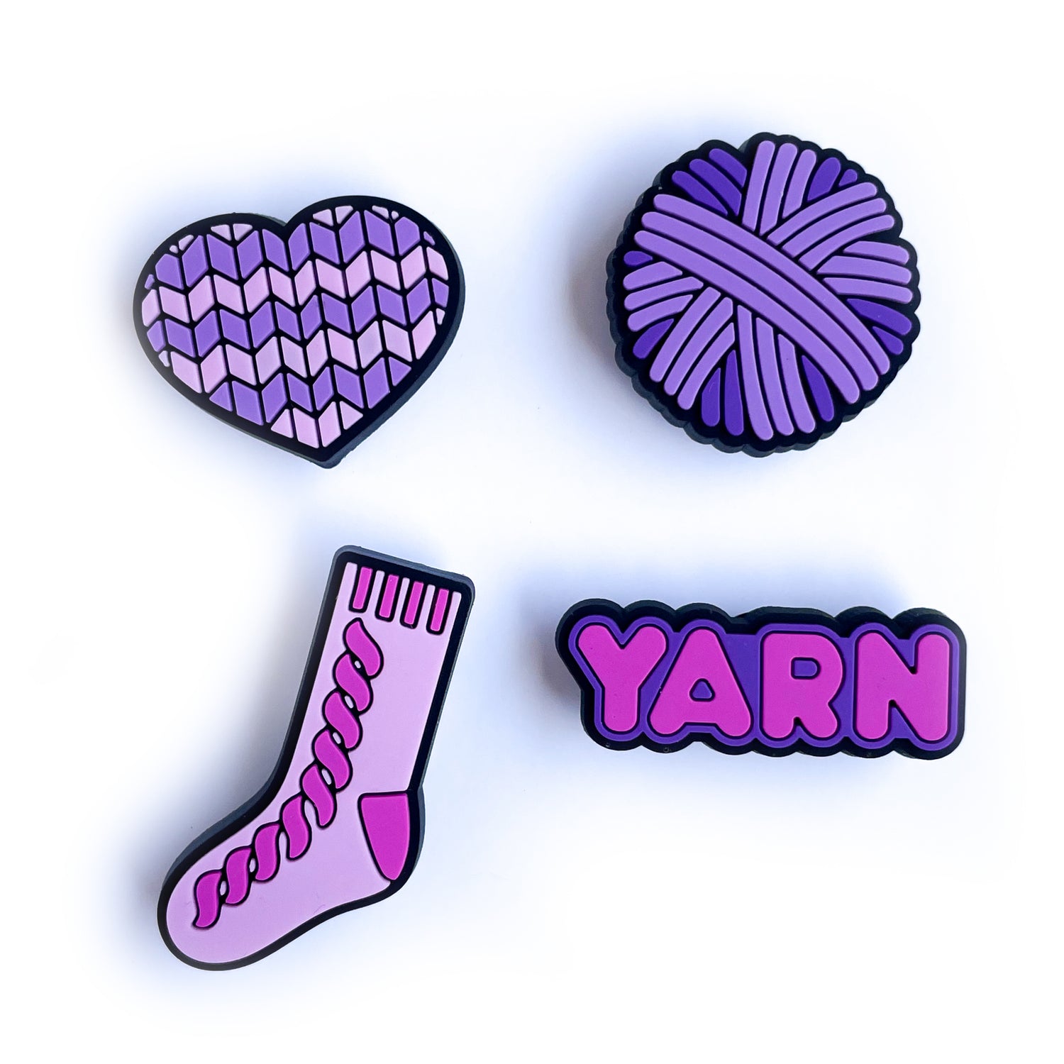 PVC charms shaped like a heart, yarn ball, sock, and the word yarn in shades of pink and purple. 