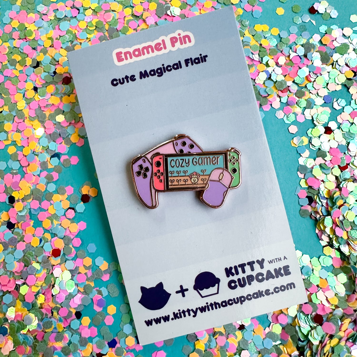 An enamel pin shaped like a Nintendo switch and a play station controller packaged on a blue card. 
