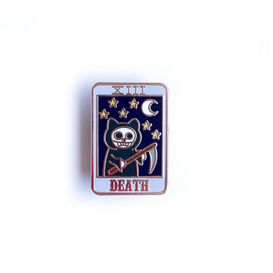 An enamel pin shaped like a tarot card with a grim reaper cat with a night sky on it and the word "Death"