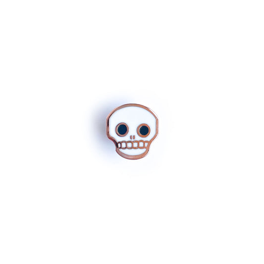 A cute cartoon skull enamel pin.