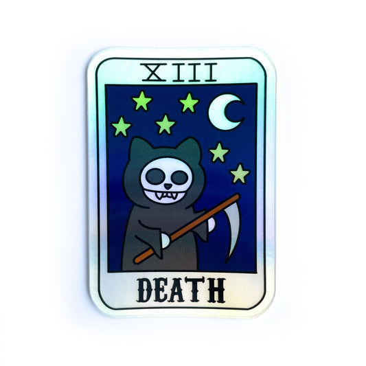 A holographic sticker shaped like a tarot card with a grim reaper cat with a night sky on it and the word "Death"
