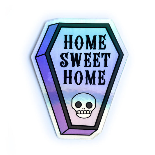 A coffin shaped holographic sticker that reads "Home Sweet Home" and has a skull on it.
