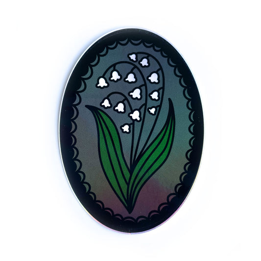 An oval shaped sticker with a lily of the valley in a lace frame. 