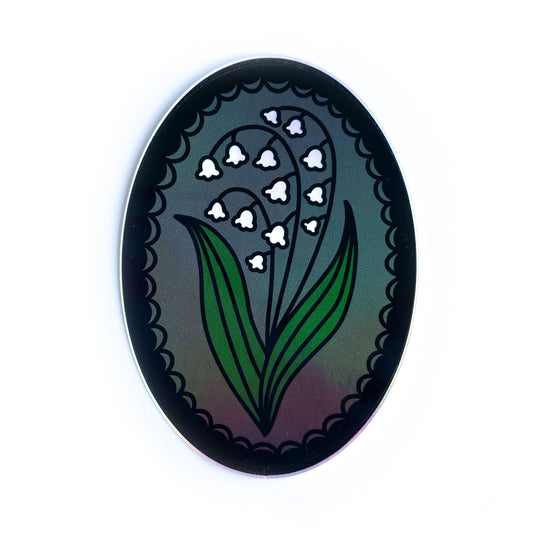 An oval shaped sticker with a lily of the valley in a lace frame.