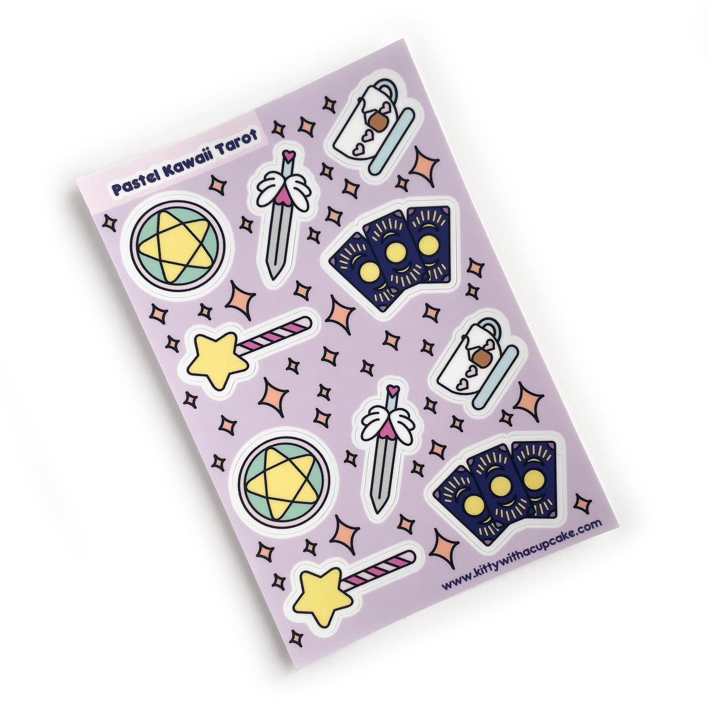 A sticker sheet with a lavender background with stickers that are cute versions of the four tarot suits, pentacles, swords, cups, wands, plus 3 fanned cards. 